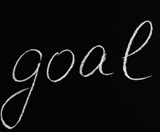 The word "goal" written in chalk using a slanted script on a chalkboard
